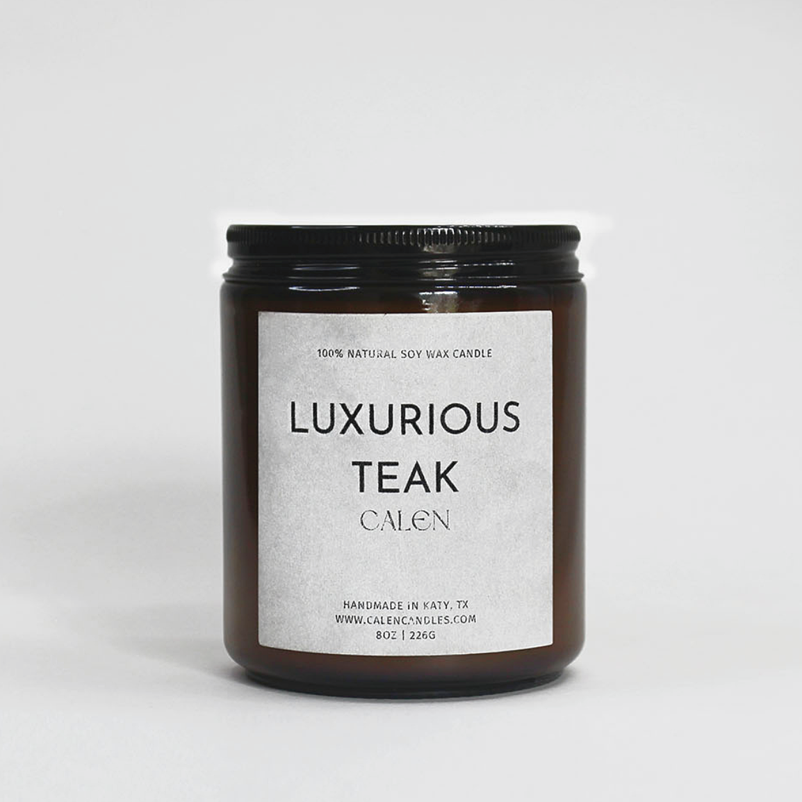 Candle jar labeled 'Luxurious Teak' on a white background
